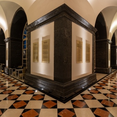 Corredor interior com piso em azulejos geométricos e paredes brancas com pedra preta