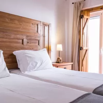 Quarto com camas individuais e cabeceira em madeira rústica