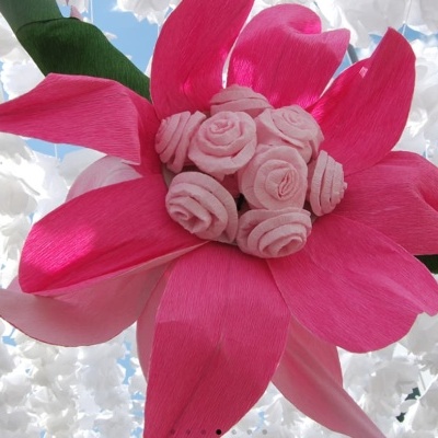 Flor decorativa de papel rosa em close com flores brancas ao fundo