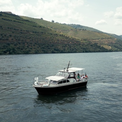 Barco de recreio preto com toldo branco em albufeira rodeada por vinhas em socalcos