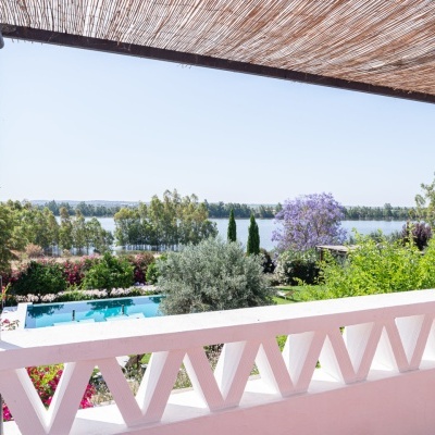 Varanda branca com vista para piscina, árvores e lago