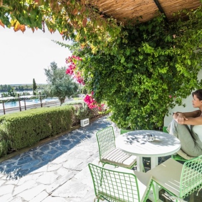 Conjunto de mesa e cadeiras na esplanada com plantas e mulher sentada