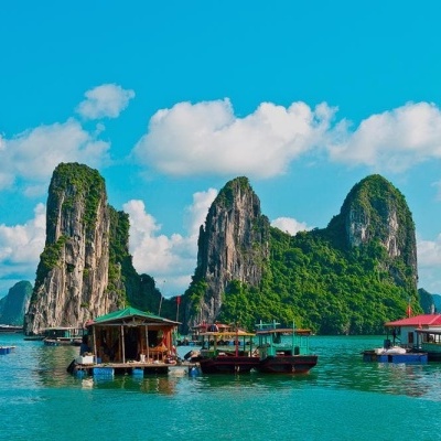 Barcos tradicionais de madeira em águas calmas junto a formações rochosas verdes