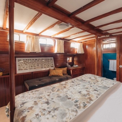 Quarto em madeira com cama, banco e cortinas brancas