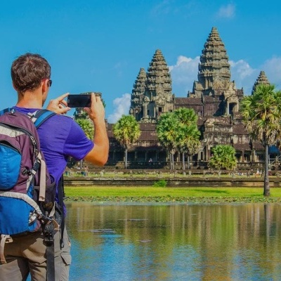 Homem com mochila tirando foto ao templo de Angkor Wat no Camboja