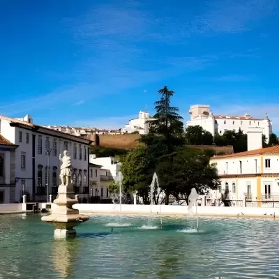 Fonte com estátua em praça e edifícios tradicionais ao fundo