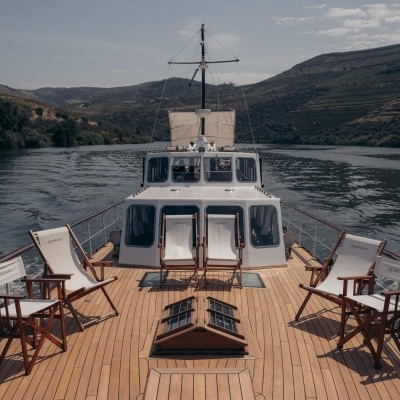Deck de barco com cadeiras de madeira e lona branca com texto pipadouro