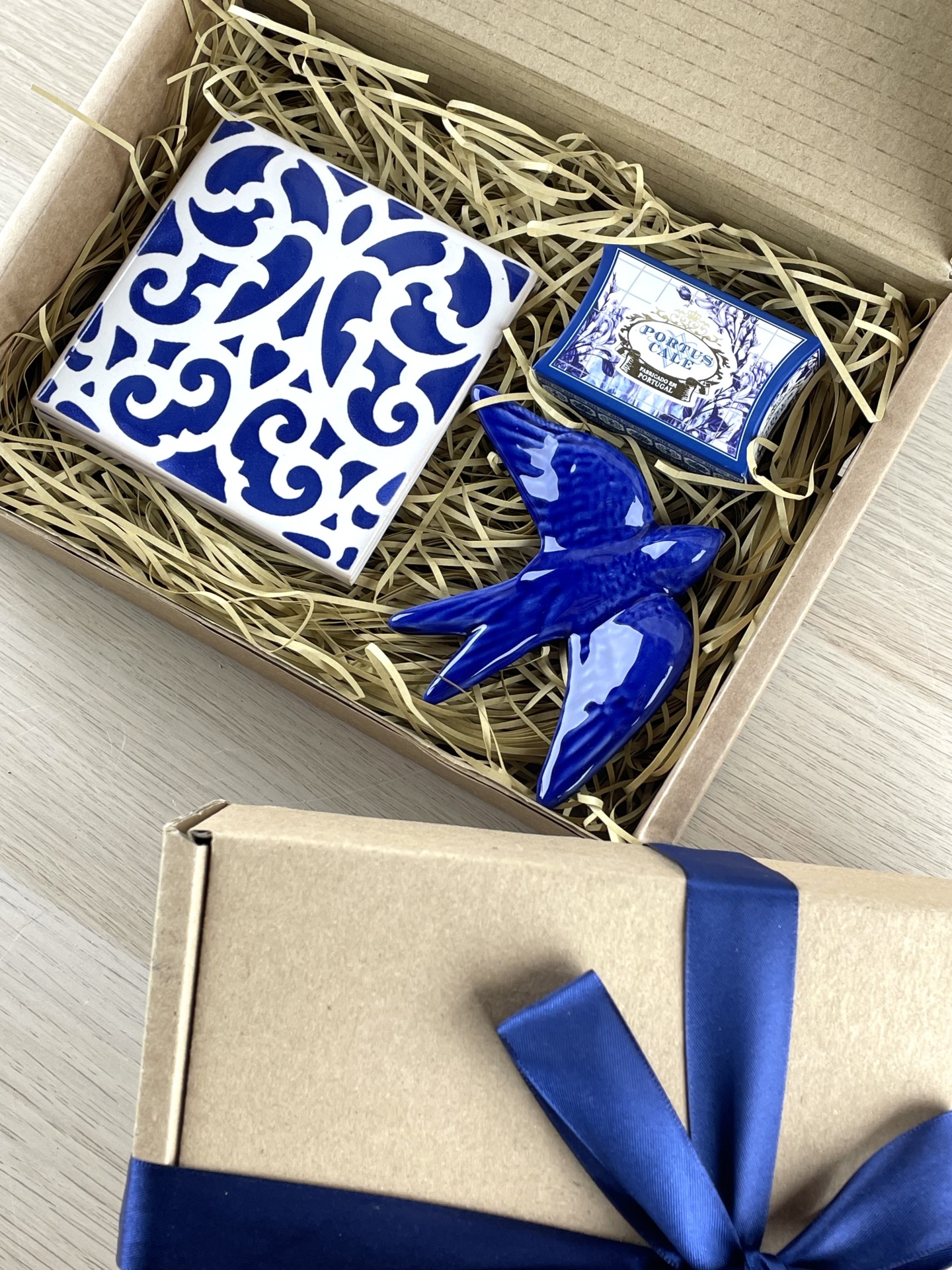 Gift box with blue and white ceramic tile, ceramic bird, and box labeled PORTUS CALE