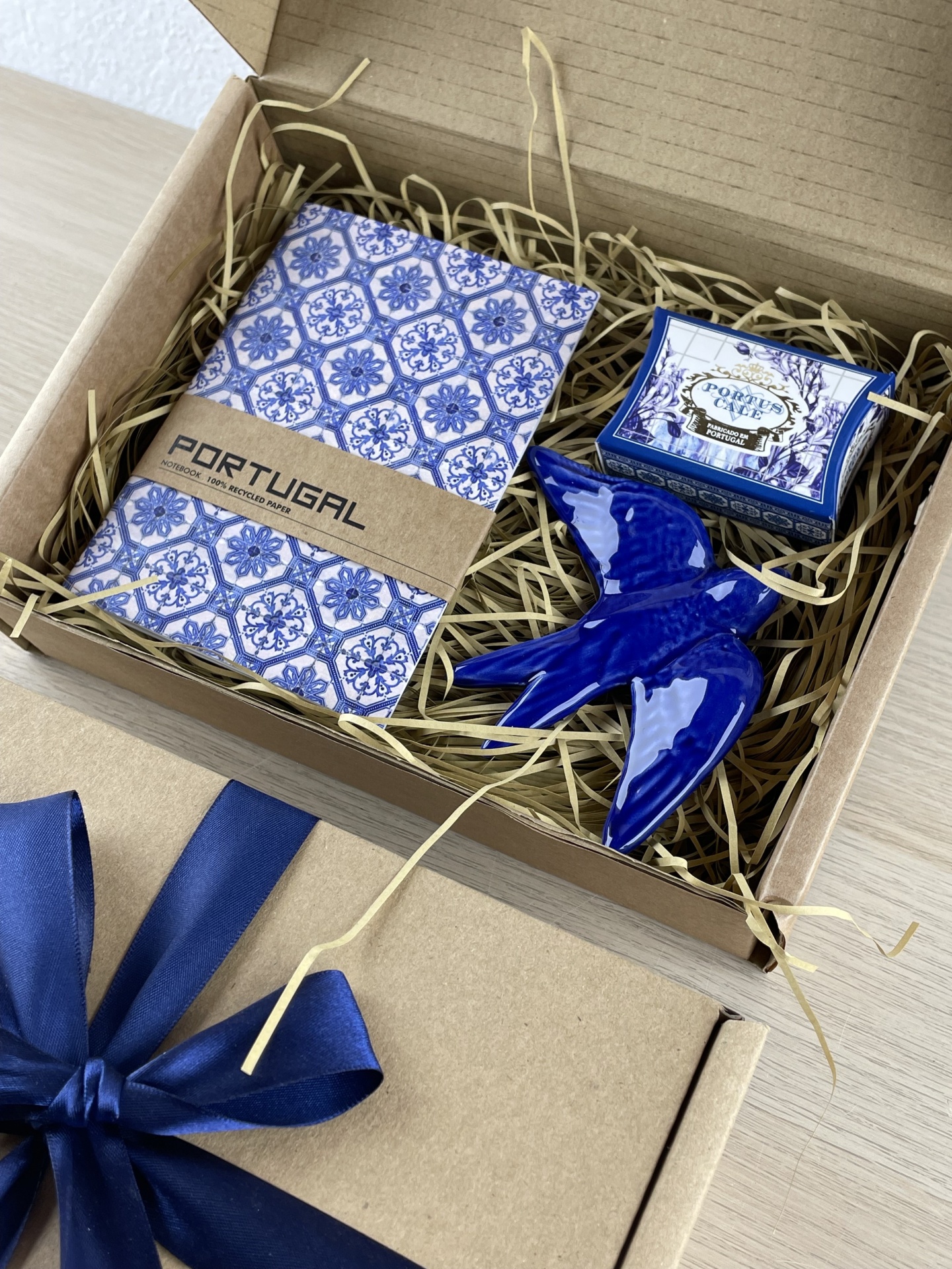 Gift box with notebook, ceramic bird, and small box labeled PORTUS CAVE