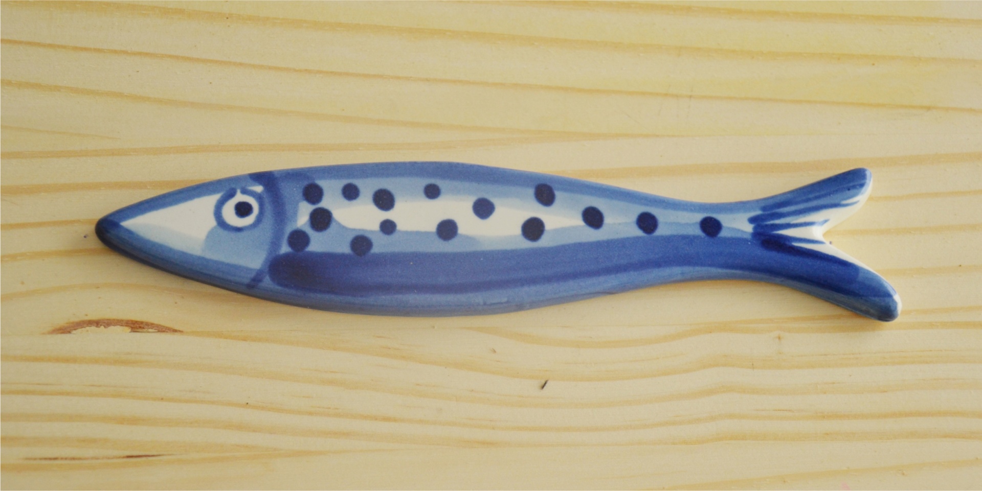 Ceramic blue fish-shaped object on light wood surface