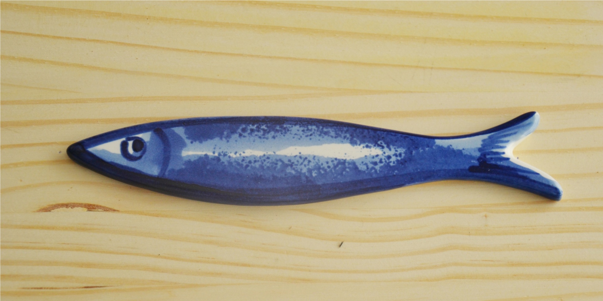 Blue ceramic fish-shaped ornament on wooden surface