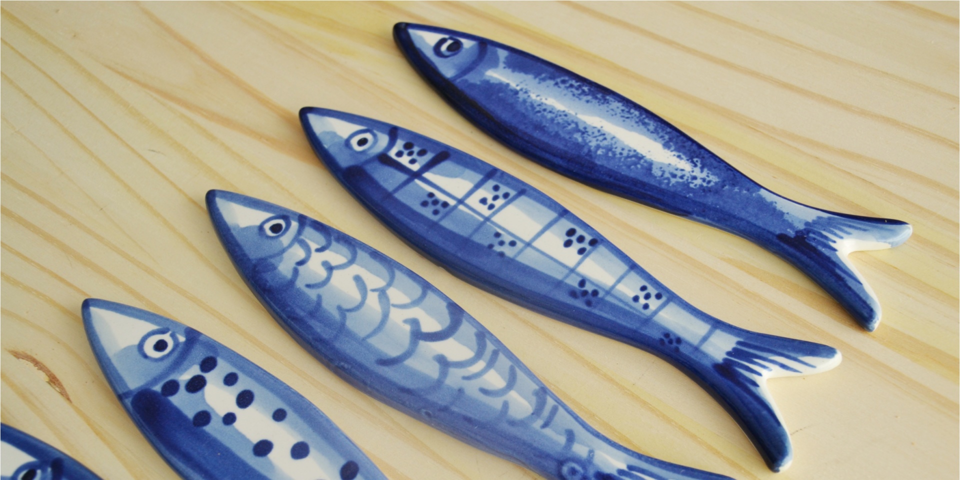 Blue and white ceramic fish-shaped objects with various patterns on wood