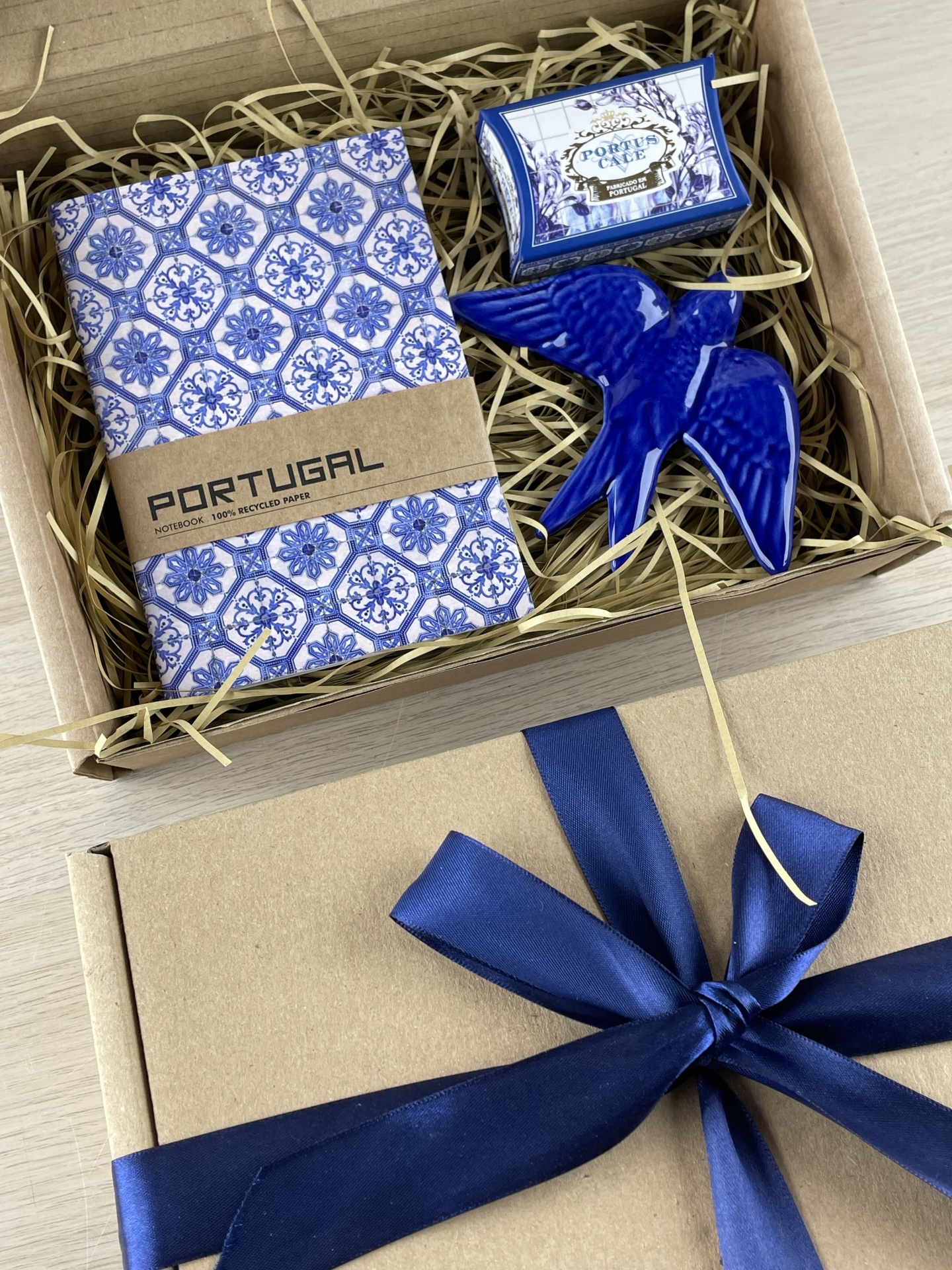 Gift box with Portugal notebook, blue ceramic bird, and Portus Cale box on packing straw
