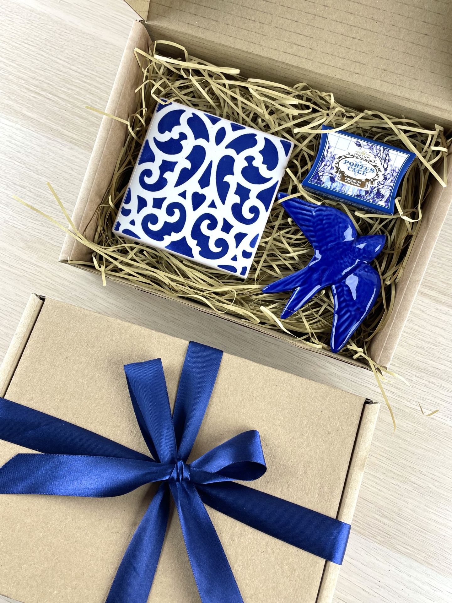 Gift box with ceramic tile, ceramic bird figurine, and small box labeled PORTUS CALE