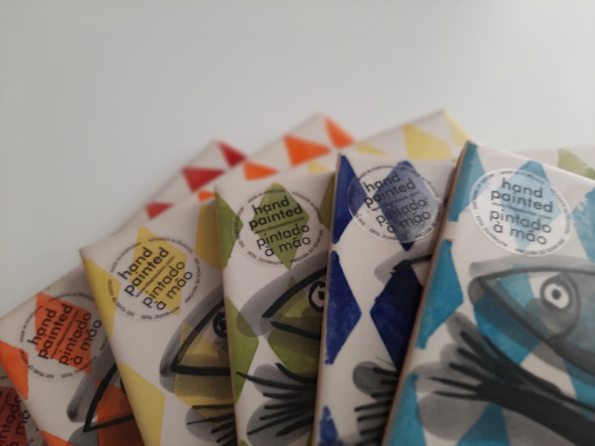 Hand-painted item packages wrapped in colorful geometric paper with fish illustrations and text stickers.