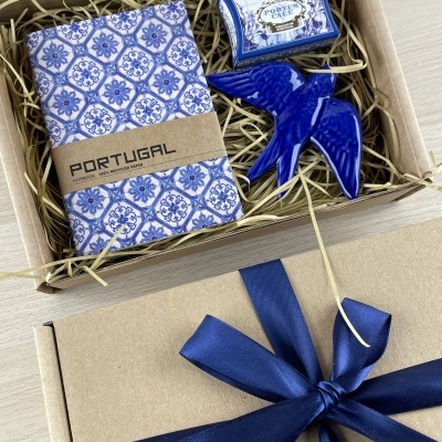 Gift box with notebook, soap, and blue ceramic bird on straw packing