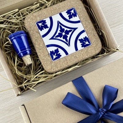 Gift box with cork coaster and blue ceramic bottle stopper in straw packing.