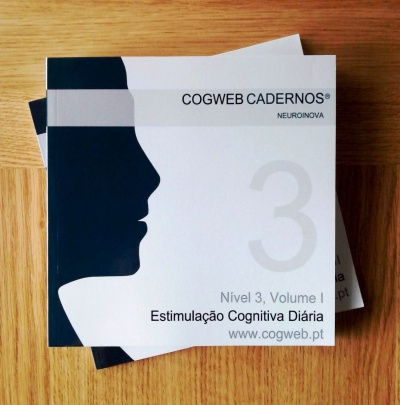 Livro branco e preto COGWEB CADERNOS Nível 3, Volume I com texto Estimulação Cognitiva Diária sobre mesa de madeira