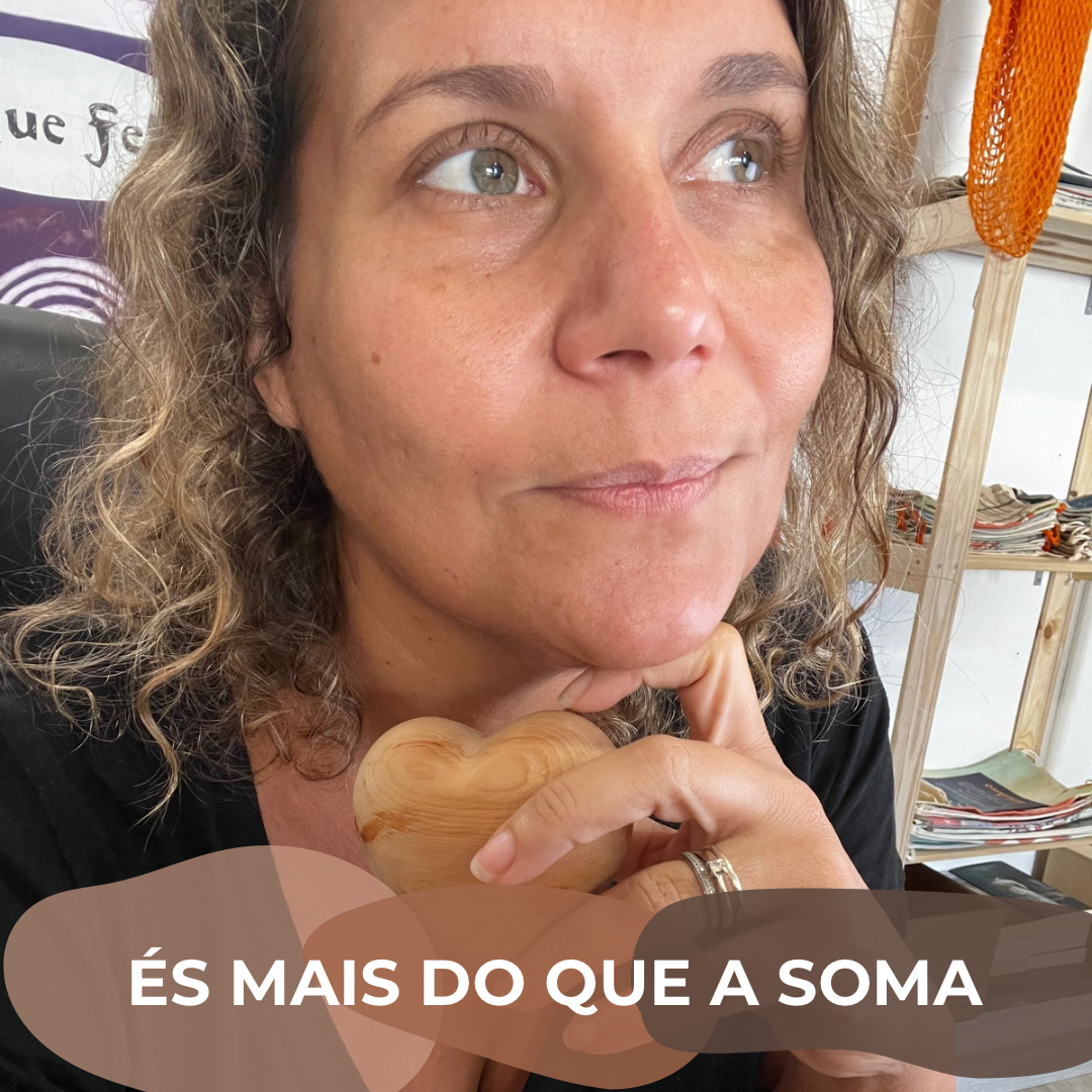 Mulher segurando objeto de madeira em forma de coração, com cabelo encaracolado e alianças douradas