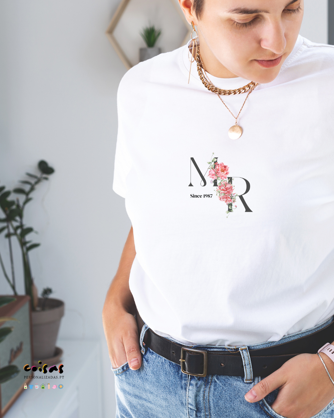 T-shirt branca com estampa floral NR e texto Since 1987, usada com calças de ganga e cinto preto