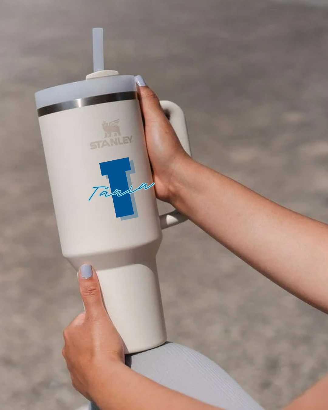 Copo térmico Stanley branco com tampa e canudo, segurado por mãos com unhas lavanda