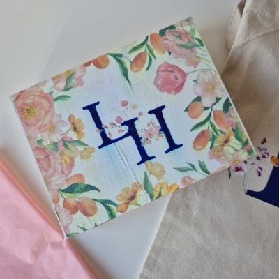 Guarda-napo floral branco com letras HI azuis