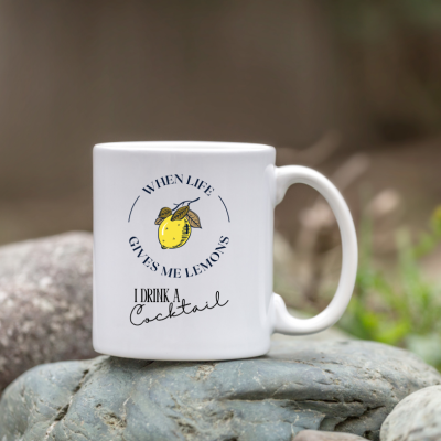 Caneca branca com texto e ilustração de limão colocada sobre pedras
