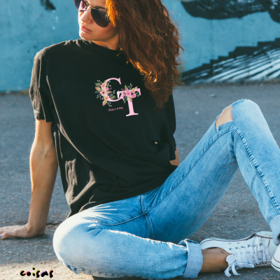 Pessoa sentada no chão a usar t-shirt preta com letras floridas 