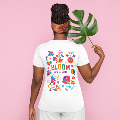 Pessoa vista de costas a usar t-shirt branca com estampa colorida floral e texto nas costas, segurando uma folha verde