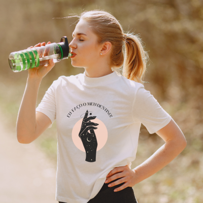 Mulher com t-shirt branca estampada e garrafa de ginásio verde a beber ao ar livre