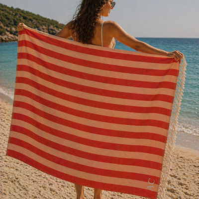 Toalha de praia às riscas vermelhas e bege com franjas na praia