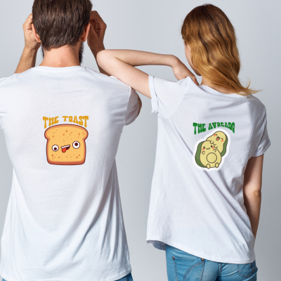 Dois adultos com t-shirts brancas, uma com imagem de tosta e outra com imagem de abacate. 