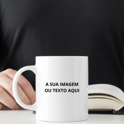 Caneca branca com texto em preto segurada ao lado de livro aberto