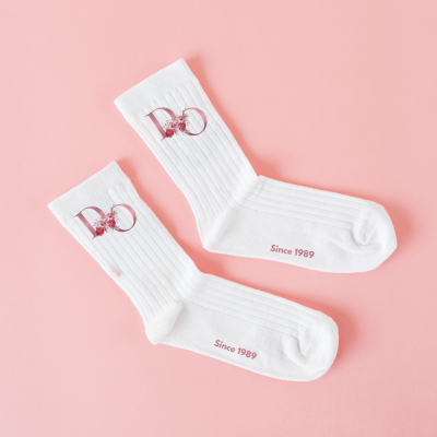 Par de meias brancas com logo e texto sobre fundo cor de rosa