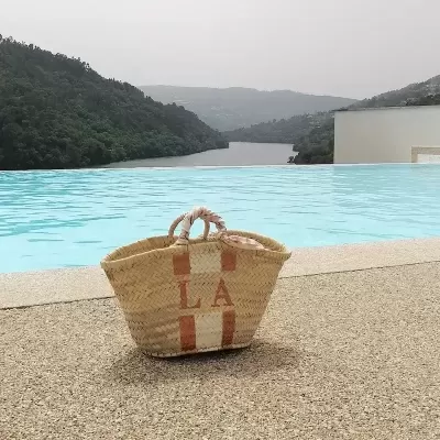 Cesto de palha com letras L e A junto a piscina com paisagem de montanhas