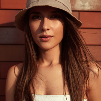 Mulher com chapéu bege claro com constelação e texto AQUARIUS em fundo de parede de madeira vermelha