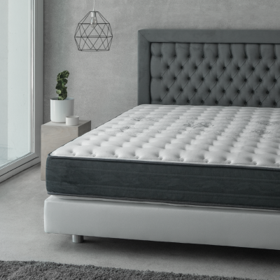 Colchão branco com laterais cinza e padrão de botões numa cama branca em quarto minimalista