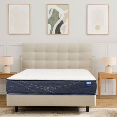 Cama estofada com colchão Orion azul, mesas de cabeceira de madeira e candeeiros num quarto minimalista