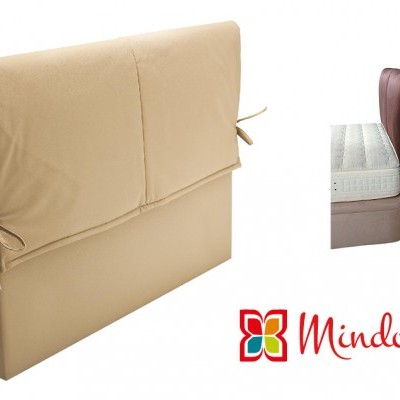 Cabeceira estofada bege com laços laterais, usada numa cama e com logo Mindol ao lado.