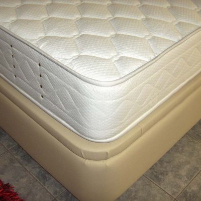 Colchão branco acolchoado sobre base estofada bege em chão de azulejos