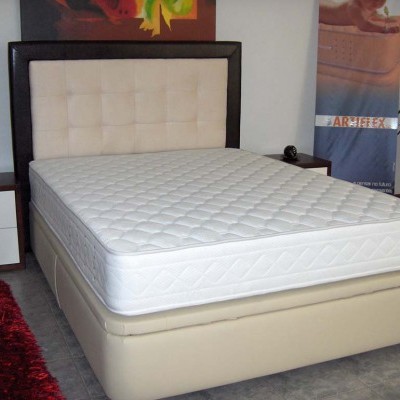 Cama de casal com colchão branco e cabeceira estofada bege