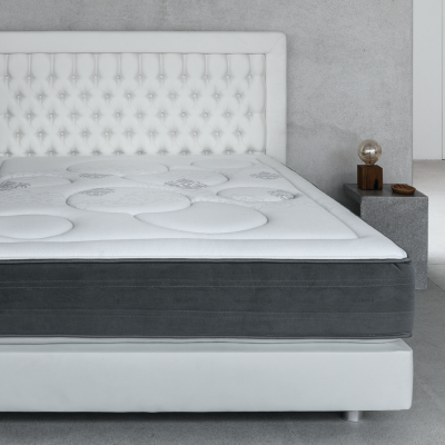 Cama de solteiro branca com colchão cinzento e cabeceira acolchoada branca num quarto moderno