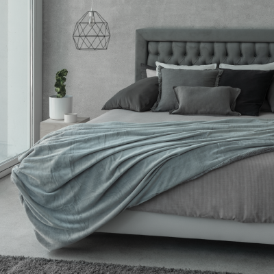 Quarto moderno com cama cinza, roupa de cama azul e cinza e candeeiro pendente