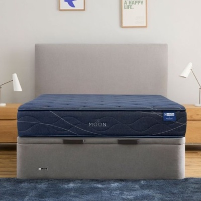 Cama com colchão azul escuro MOON e base cinza em quarto com mesas de cabeceira de madeira.