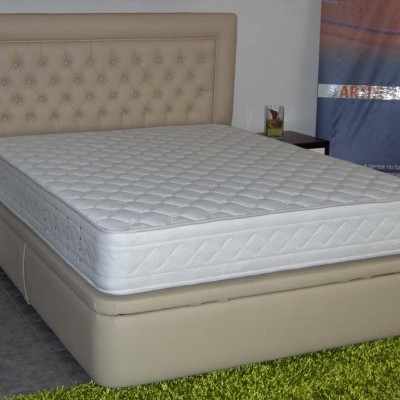 Cama de casal com colchão branco e cabeceira estofada bege