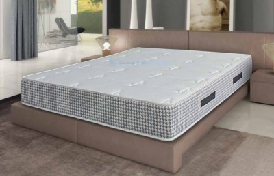 Colchão branco com laterais de padrão xadrez cinza, branco e azul em cama caixa bege num quarto moderno