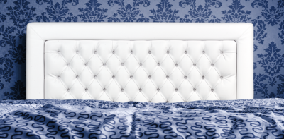 Cabeceira de cama branca capitonê contra parede azul com papel de parede floral