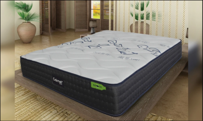 Colchão com capa branca e laterais pretas numa cama de madeira dentro de um quarto