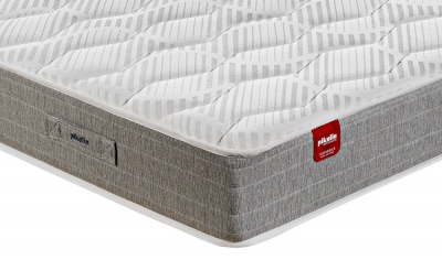 Colchão branco acolchoado com laterais cinza e etiqueta vermelha