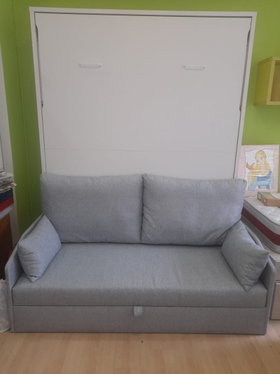 Sofá cinzento claro com almofadas e braços numa sala com parede verde e branca